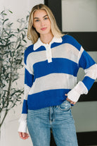 A blue and white striped henley with a collared neckline and button closures, worn by a model with jeans.