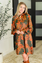 Woman wearing a floral dress with orange and green pattern indoors.
