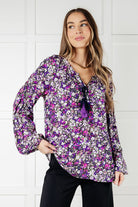 Purple ditsy floral blouse with v-neck and bubble sleeves, worn by a model