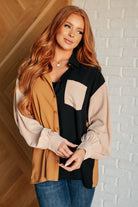 Woman wearing a color-blocked shirt against a white brick wall.