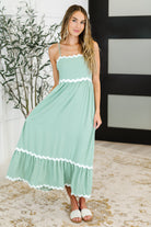 Woman wearing a mint green dress with white trim indoors.
