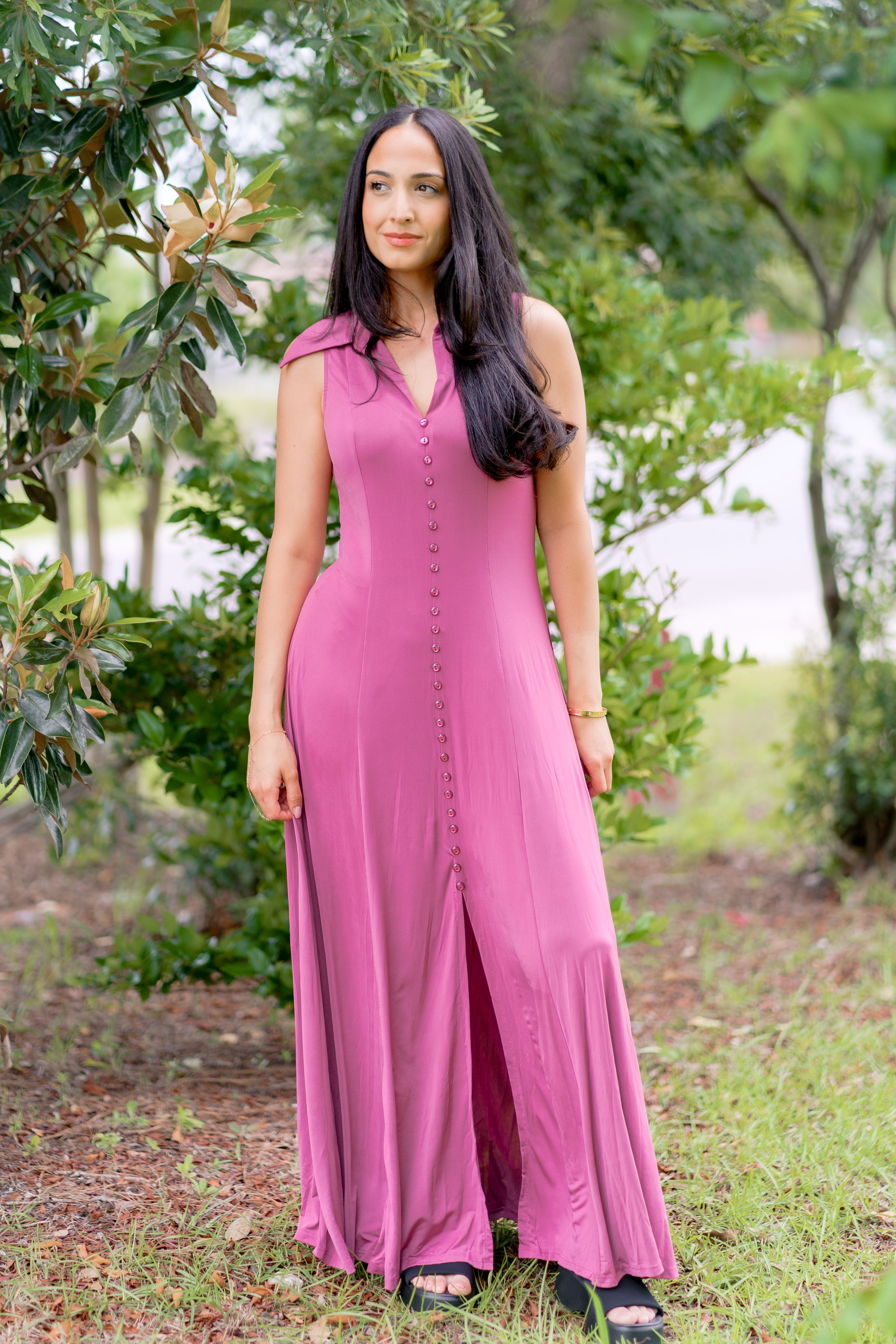 Woman wearing a grape-colored, sleeveless, button-front, flowy dress standing outdoors.