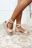 A pair of blush pink beige platform sandals with gladiator-style ankle straps and a sole twine detail, displayed on a person's feet.