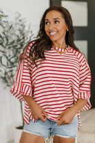 Woman wearing a red and white striped shirt and denim shorts indoors.