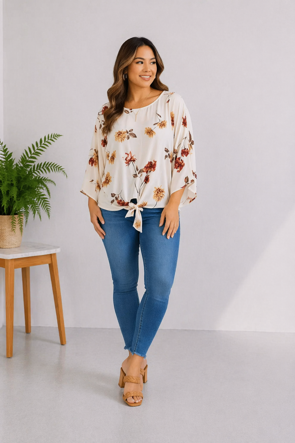 Model wearing a multi-colored top with floral pattern, 3/4 sleeves, and a front tie detail.
