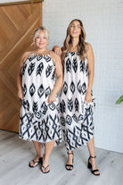 Two models wearing sleeveless maxi dresses with a geometric pattern, silver hardware, and a square neckline.
