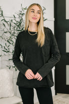 Black long sleeve top with drop shoulders, exposed seams, and a patch pocket.