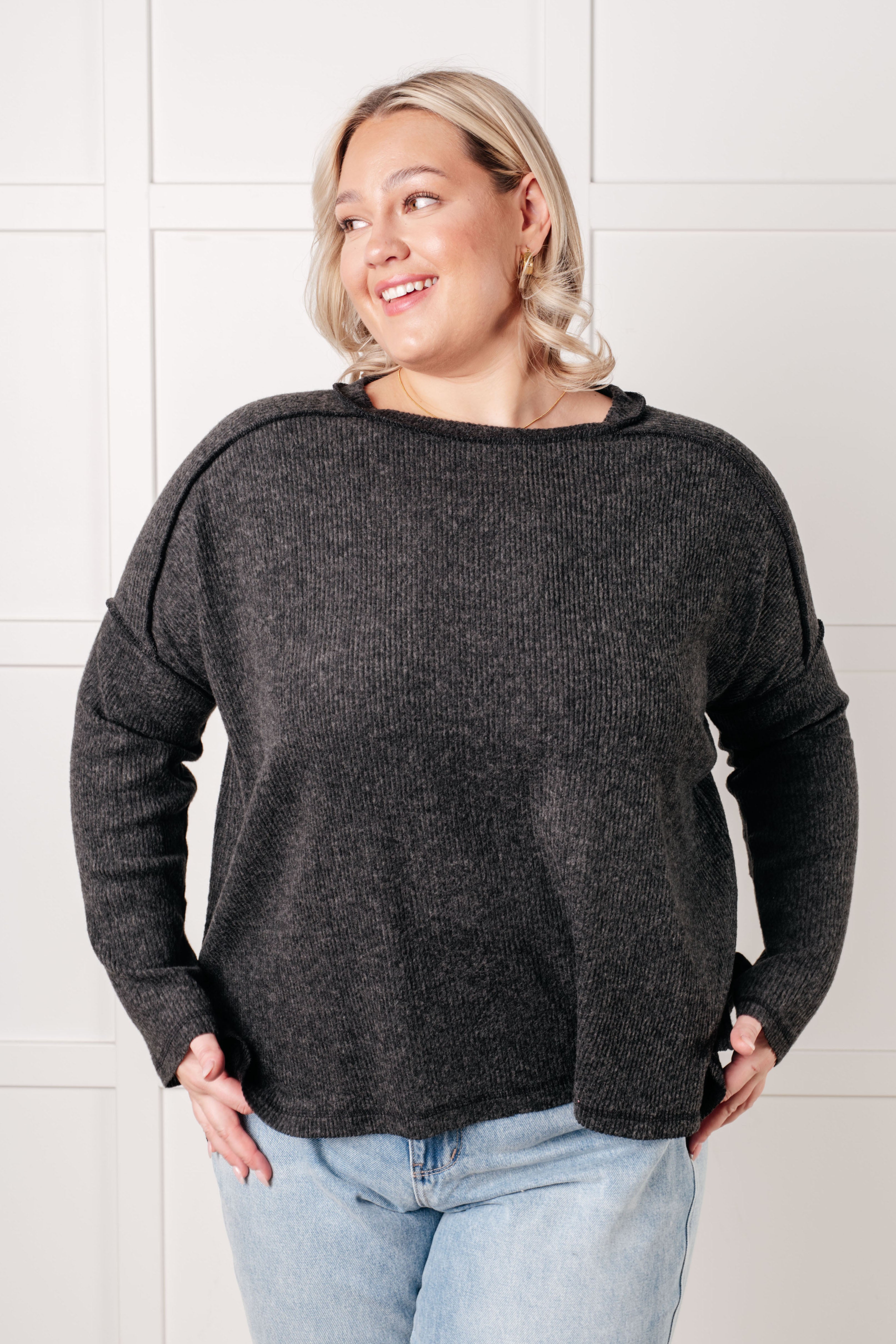 Woman wearing a black sweater and light blue jeans against a white background