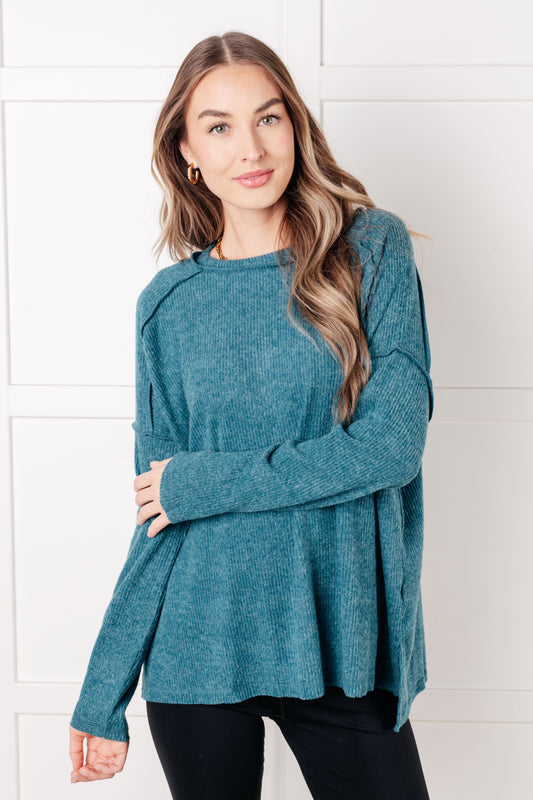 Woman wearing a teal sweater against a white tiled wall
