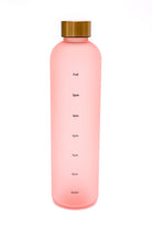 Pink translucent water bottle with gold cap and drink reminders on the side.