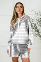 A female model wearing a striped long sleeve top and matching shorts set with a round neckline and side pockets.
