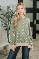 A green pullover with a cable ribbed texture, contrast round neckline, and drop shoulders.
