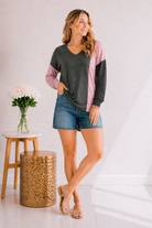 Model wearing a colorblock long sleeve top with a V-neck in olive, pink, and charcoal.