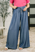 Wide-leg blue bottoms with a high-waisted fit, button closures, and pleat details.