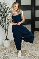 Woman wearing a navy jumpsuit with a white background