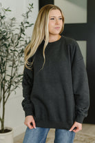 Woman wearing a black sweatshirt in an indoor setting with a plant in the background