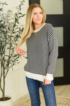 Woman wearing a black and white striped sweater with a blurred indoor background