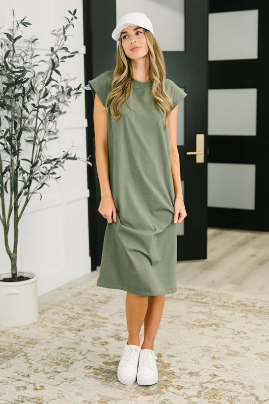 Woman wearing a green dress and white sneakers indoors.