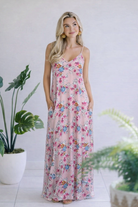 Maxi dress in dusty pink with floral print, v-neckline, spaghetti straps, and side pockets.
