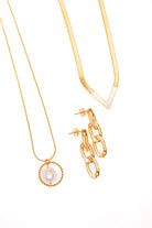 A gold-plated stainless steel pearl pendant necklace, a gold-plated stainless steel pearl v-necklace, and gold-plated stainless steel paper clip earrings, displayed against a white background.