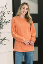 Orange oversized corded sweatshirt with a relaxed fit, banded round neckline, drop shoulders, and ribbed cuffs.