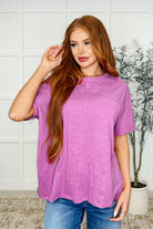 A woman wearing a relaxed fit hot magenta tee with a round neckline, sleeve cuffs, and a front patch pocket.