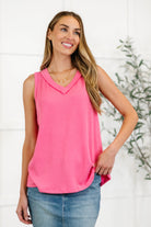 A woman wearing a strawberry pink ribbed knit tank top with a V-neckline and sleeveless design.