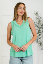 A woman wearing a sleeveless, Tiffany blue ribbed knit tank top with a banded, crossed V-neckline and exposed seam details.