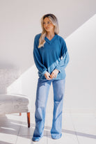 Model wearing a dusty teal long sleeve top with v-neck and puffed sleeves.