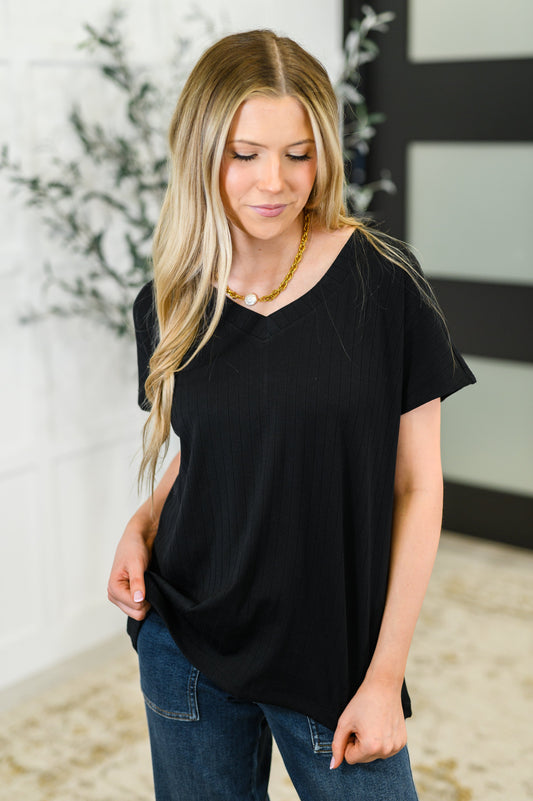 Woman wearing a black top and blue jeans with a blurred background