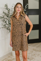 Woman wearing a leopard print dress indoors with decorative elements.