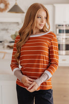 Woman wearing an orange and white striped shirt in a kitchen.