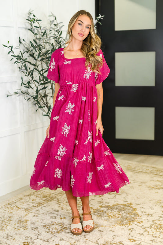 Woman wearing a pink dress with white floral patterns indoors.
