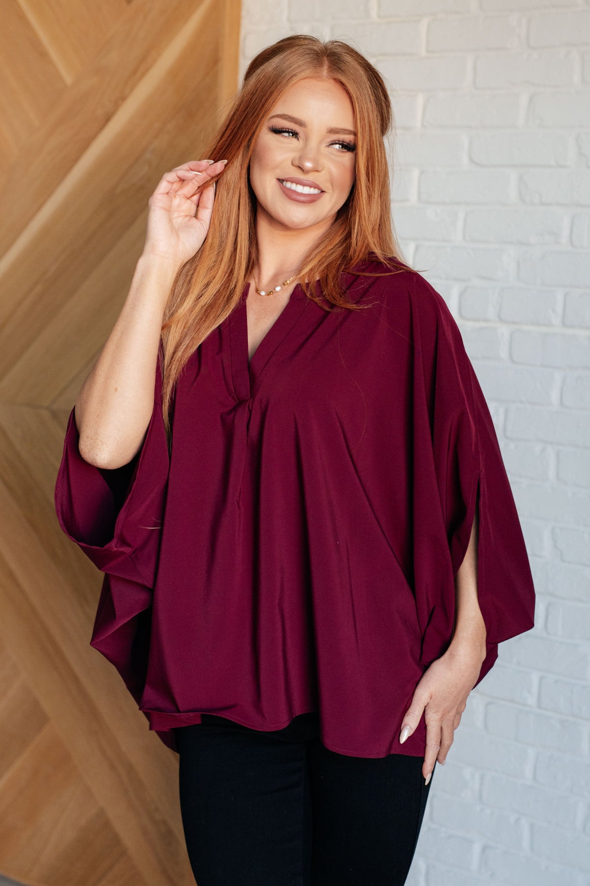 Wine-colored blouse with V-neck and batwing sleeves, styled in an oversized fit.