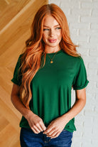 A woman wearing a green Uptown Crew T-Shirt with short sleeves and a round neckline.