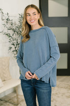 Model wearing a dusty blue cable ribbed knit top with a relaxed drop shoulder fit and a banded round neckline.