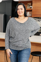 Charcoal ribbed top with boat neckline and dolman sleeves, worn by a model in a kitchen setting.