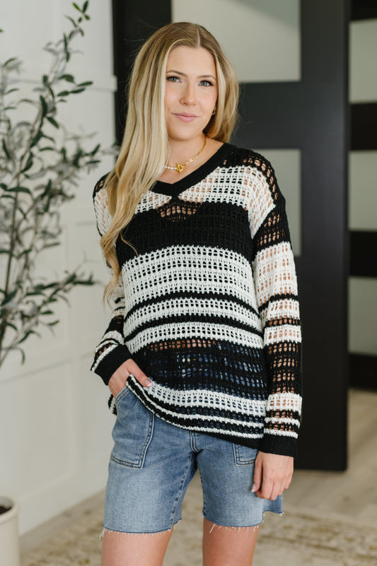 Woman wearing a black and white striped sweater with denim shorts indoors.