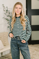 A woman wearing a hunter green and white striped button-down sweater with a collared neckline.