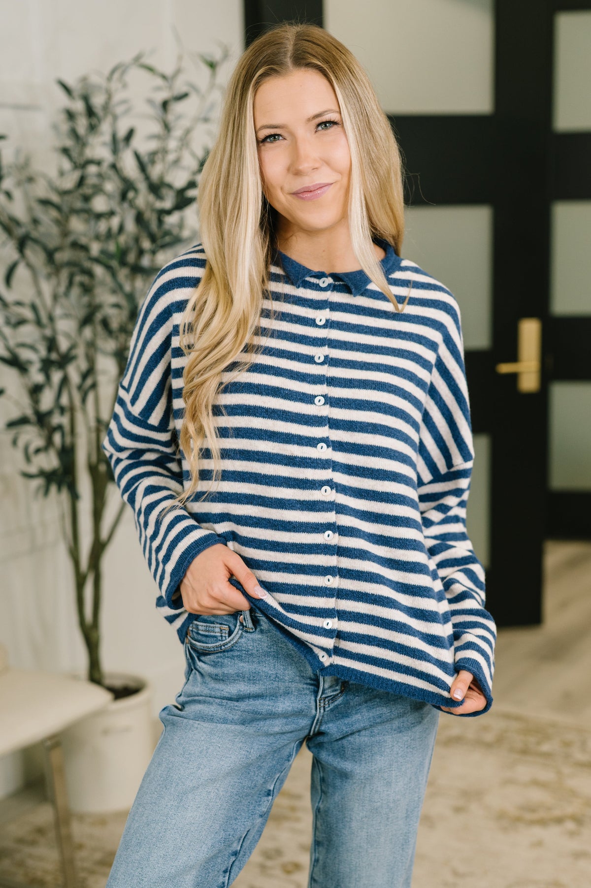 Model wearing a navy striped button-down sweater with a collared neckline and relaxed fit.