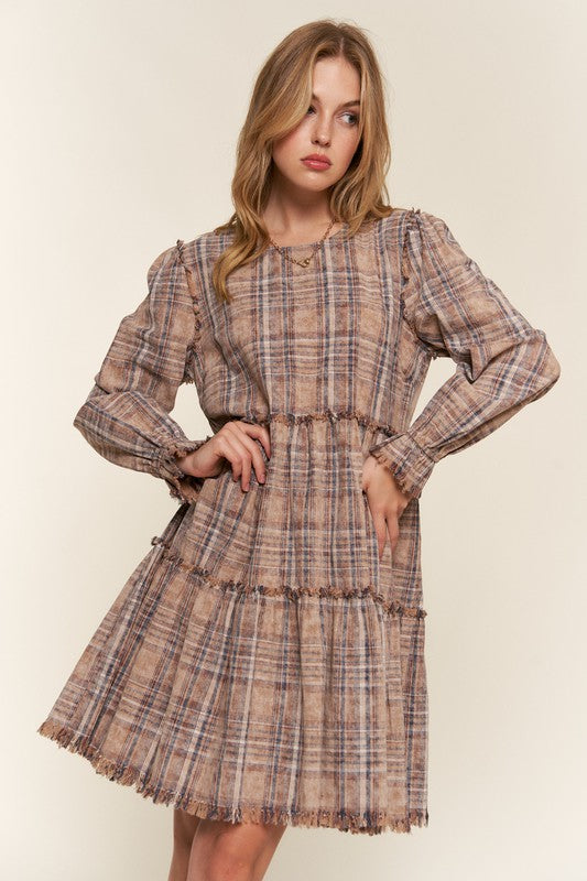 Woman wearing a plaid dress against a plain background