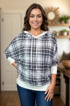 Woman wearing a black plaid 3/4 sleeve hoodie with drawstring and relaxed fit.