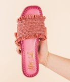 A hand holding a pink woven sandal with a glitter border on the footbed.