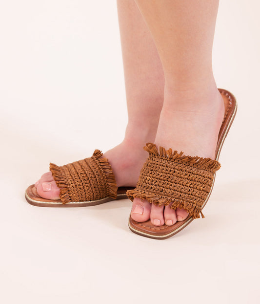 Women wearing tan woven sandals with leather footbed against a white background