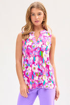 Woman wearing a sleeveless magenta tank top with a floral pattern, a split neckline, and a mandarin collar.