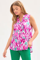 A female model wearing a sleeveless, v-neck, floral patterned tank top in pink and teal colors with a mandarin collar.