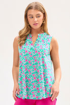 Woman wearing a floral sleeveless top and pink pants on a light background