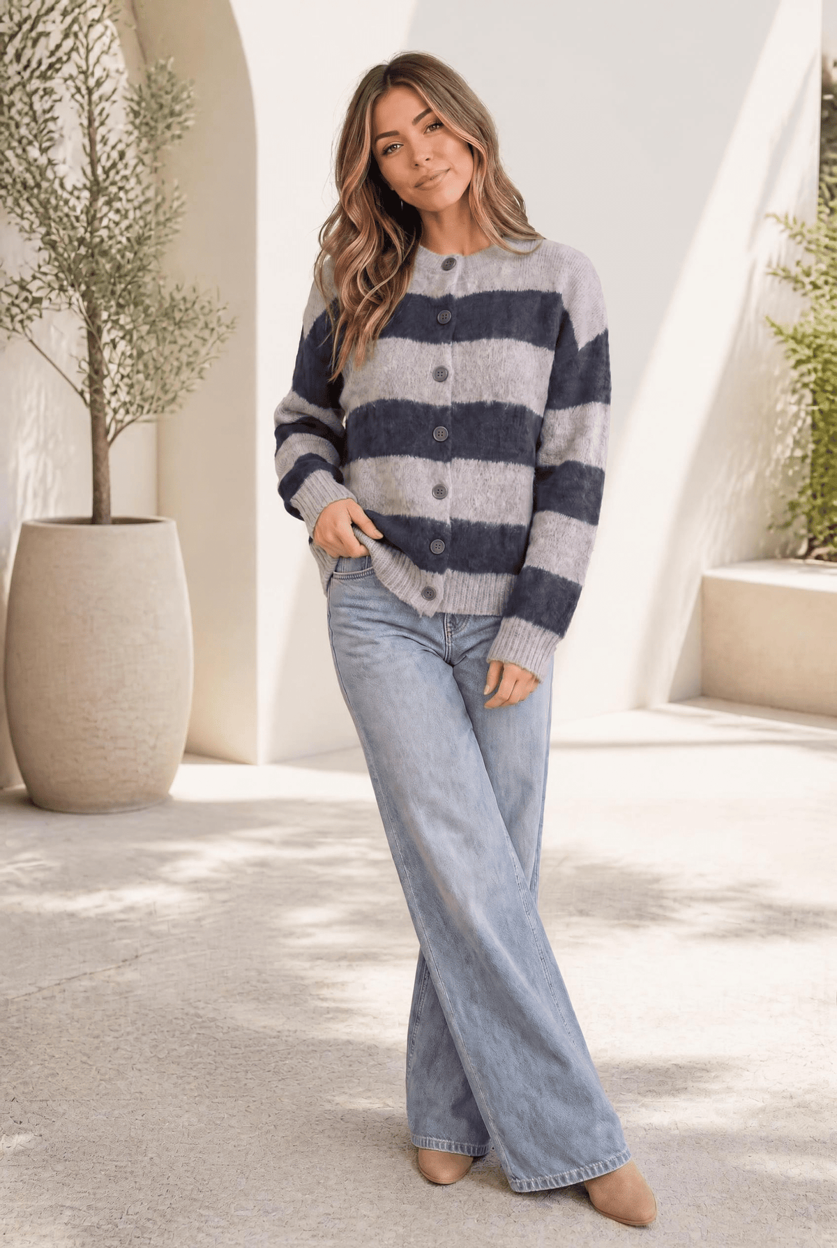 A woman wearing a fuzzy oversized cardigan with navy and grey wide stripes, buttoned front, and ribbed cuffs and hem.