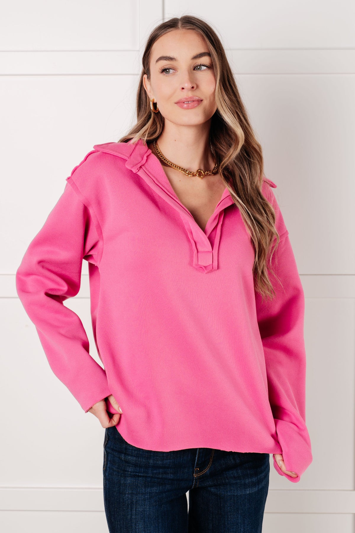 Hot pink collared pullover with a v-neck, drop shoulders, and raw hem, worn by a model.