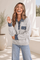 A cozy knit pullover with denim collar, cuffs, and chest pocket, worn by a smiling woman.